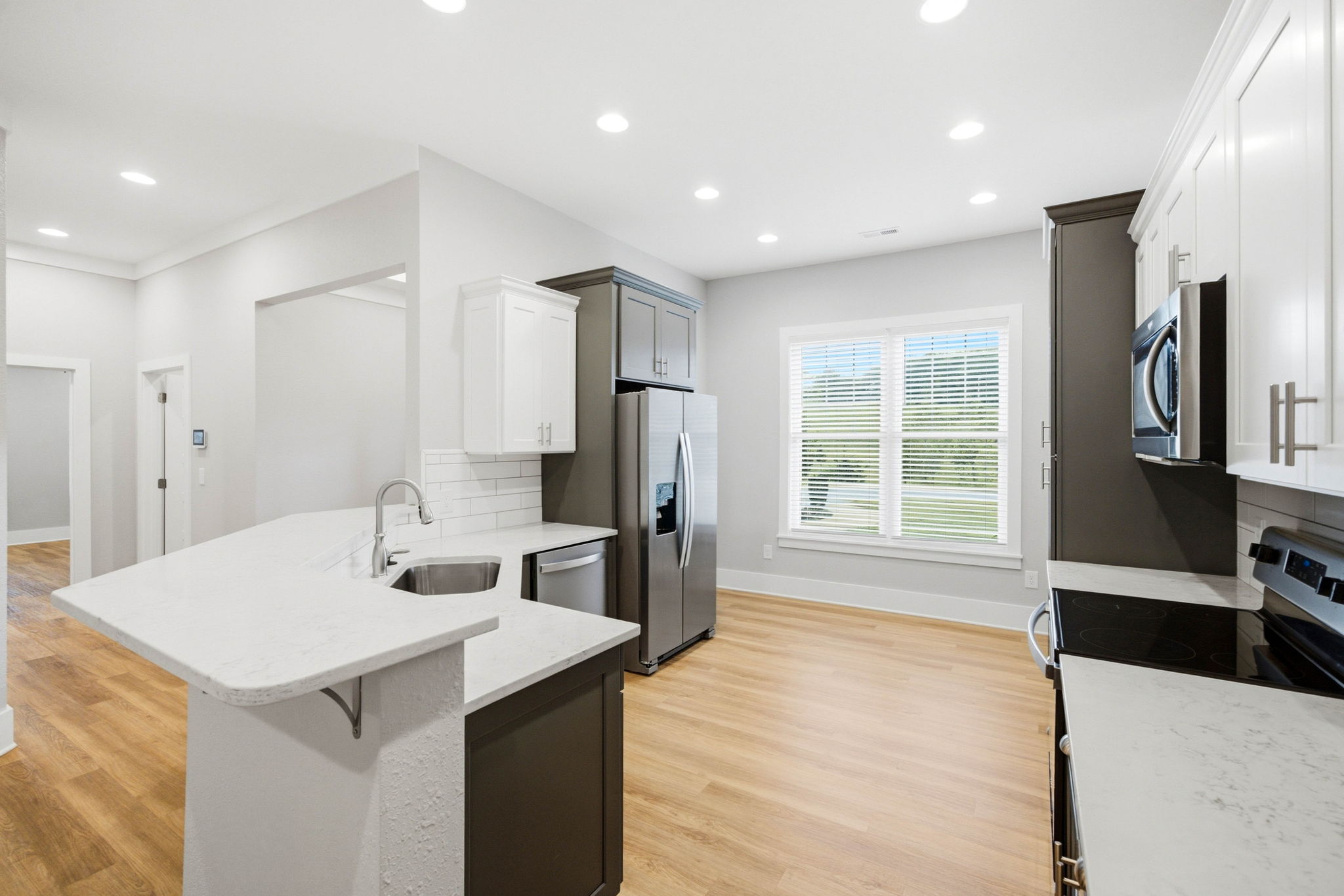 Bright kitchen with quartz serving bar, stainless appliances, pantry storage, and natural light.