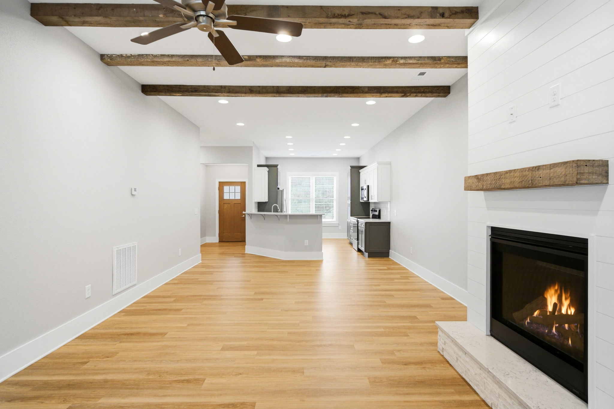 Generous open-concept living space with fireplace, decorative beams, and room for full-size furniture.