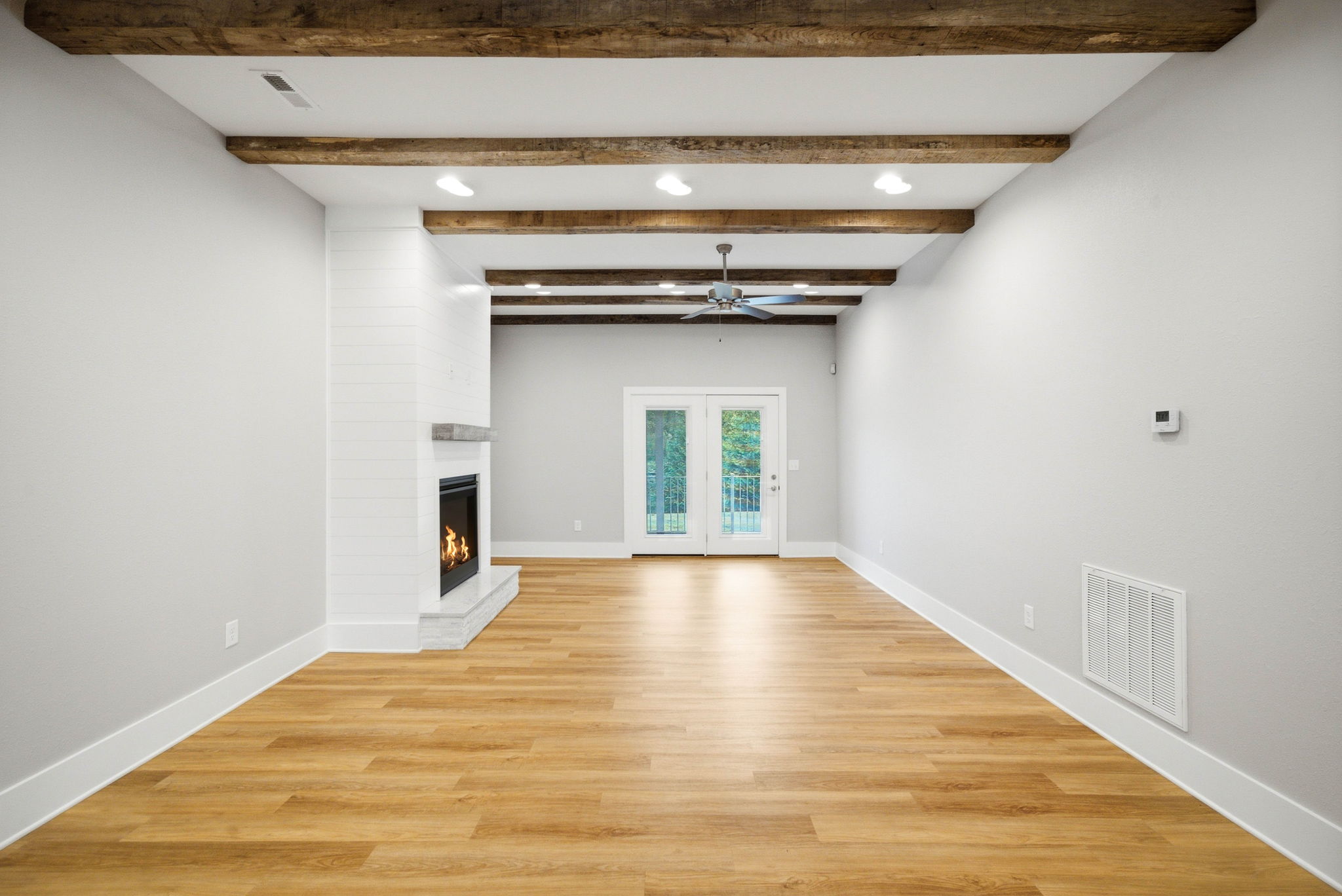 Spacious living room with gas fireplace, decorative ceiling beams, and direct access to the covered rear patio.