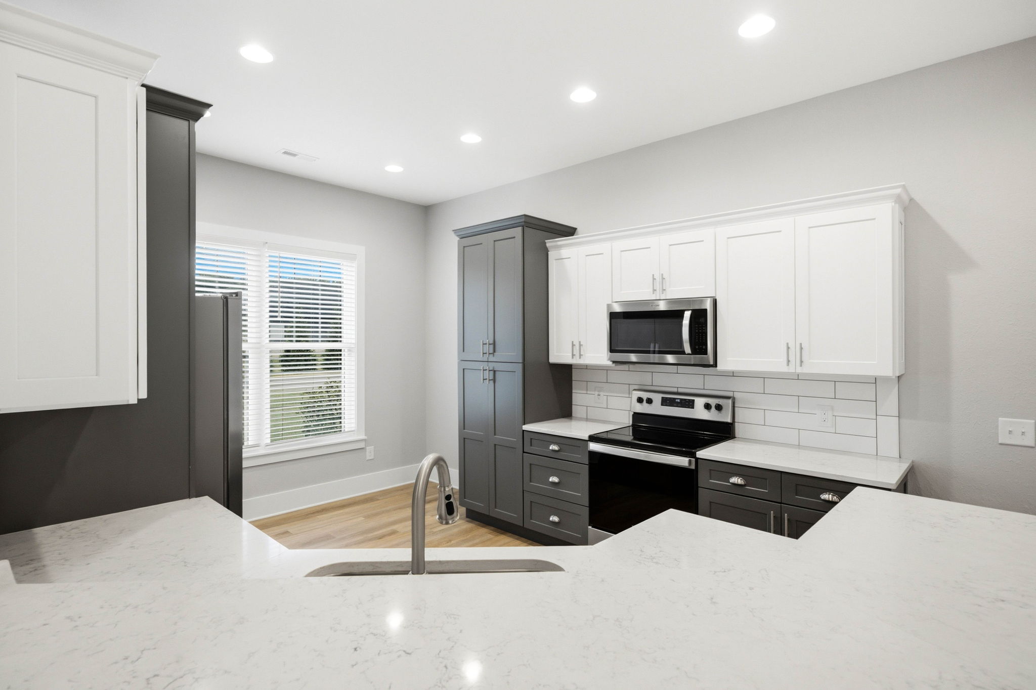 Well-appointed kitchen with quartz countertops, two-tone cabinetry, stainless appliances, and abundant storage.