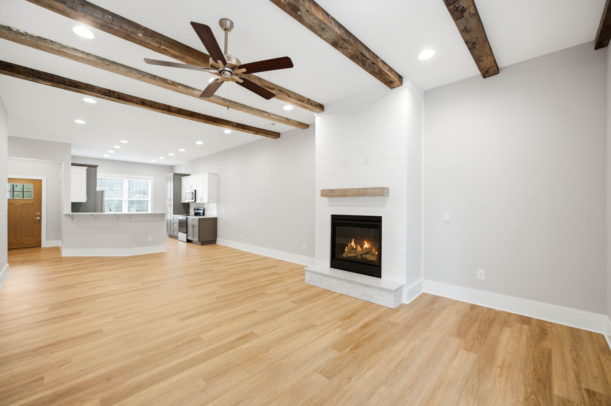 Open living area with gas fireplace, ceiling beams, and an easy flow into the kitchen.