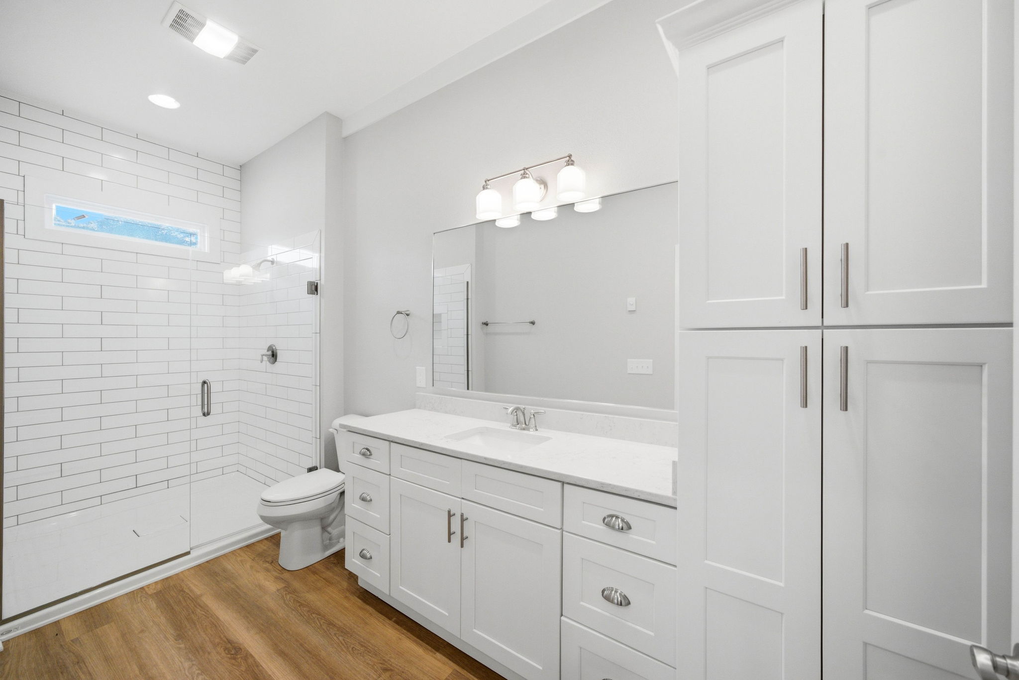 Primary bath with oversized tiled walk-in shower, generous vanity, and built-in storage.