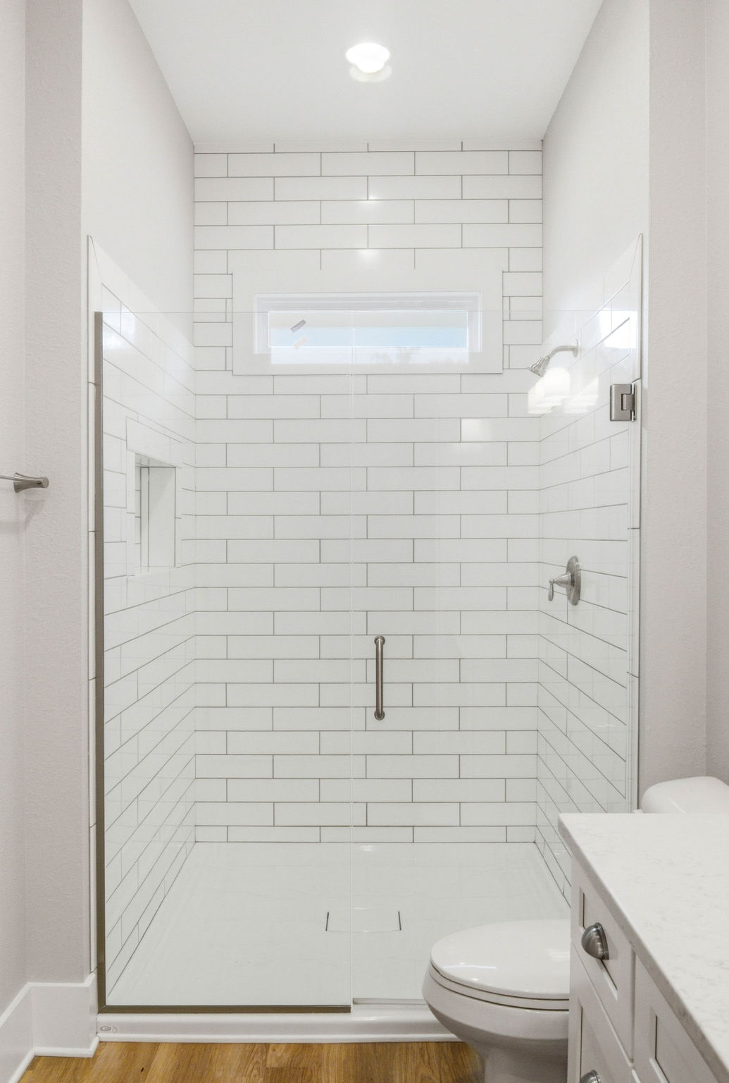 Oversized tiled walk-in shower with low threshold, glass enclosure, and built-in niche.